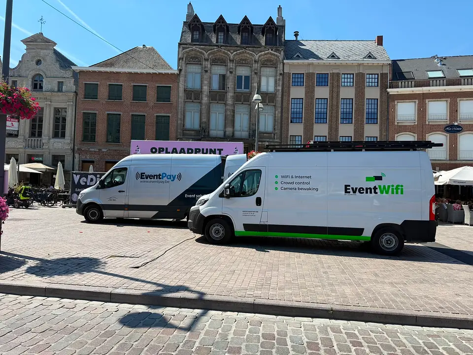 Bestelwagens van EventWiFi en EventPay op een stadsplein tijdens de opbouw van een stadsfeest