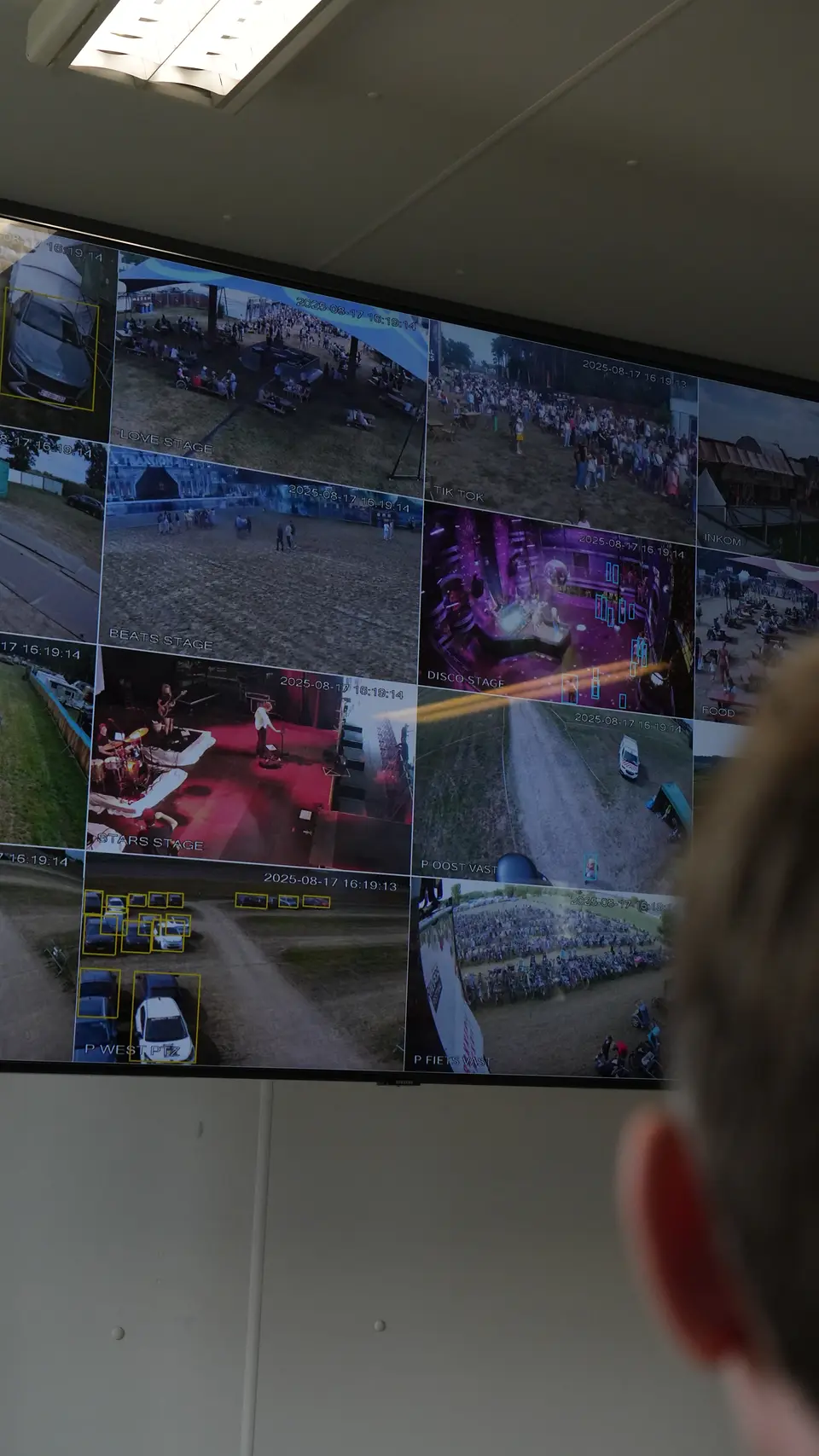 Operator volgt live camerabeelden van een festival op een videowall in de controlekamer