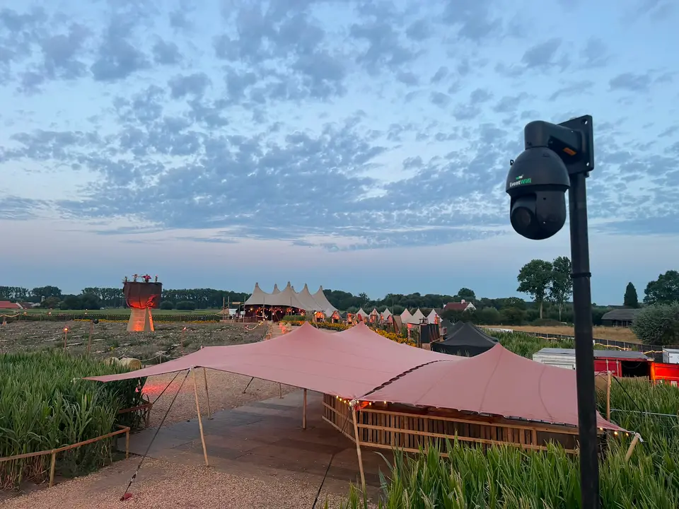 Festivalterrein bij schemering met stretchtenten en een PTZ camera van EventWiFi op een mast