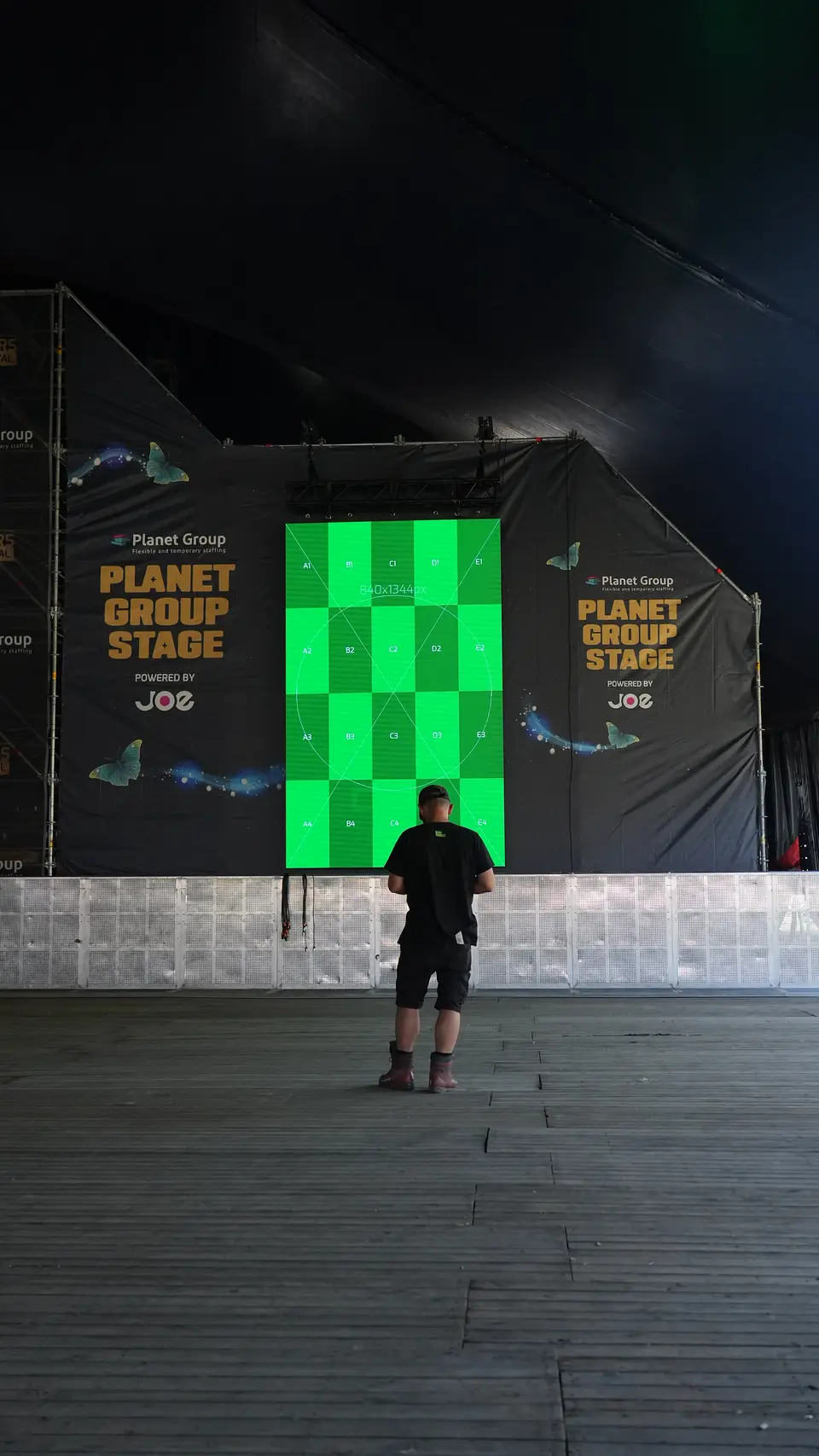 Groot LED scherm naast een festivalpodium toont programmatie en sponsorboodschappen