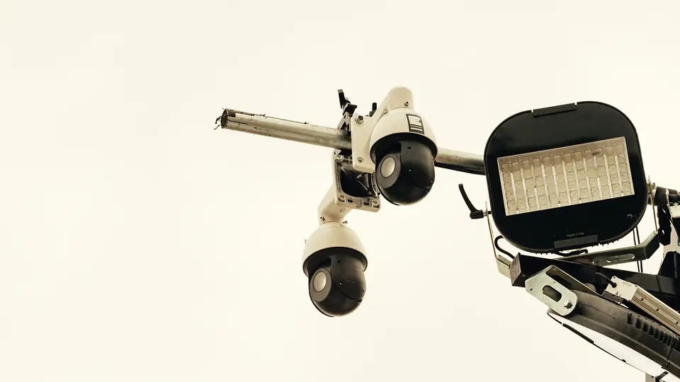 Cluster bestuurbare PTZ camera's en een schijnwerper op een mast tegen een heldere lucht