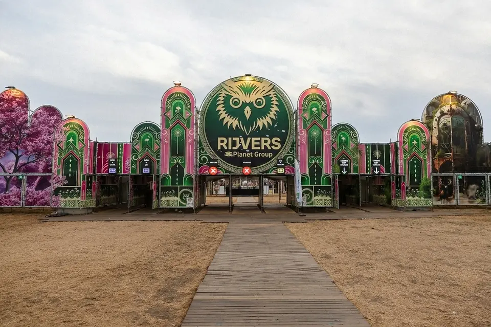 Hoofdingang van Rijvers Festival met de grote uilenpoort en het vlonderpad dat er naartoe loopt