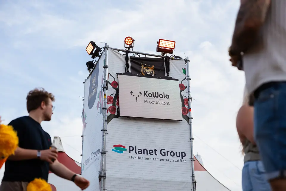 Bezoekers lopen voorbij de stellingtoren met LED scherm op Rijvers Festival