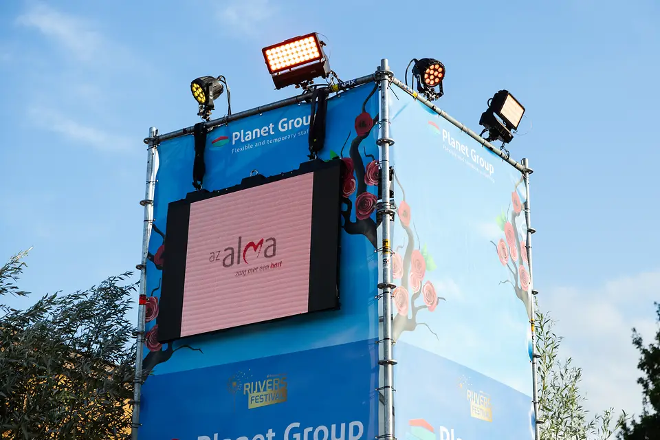 LED scherm in een stellingtoren op het terrein van Rijvers Festival, met schijnwerpers erboven