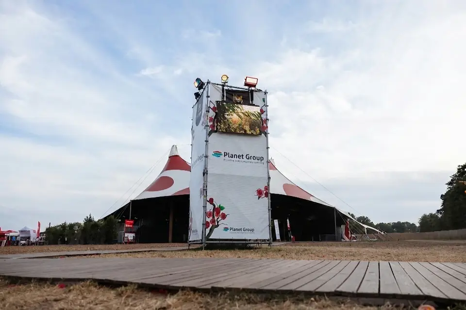 Stellingtoren met LED scherm bij de festivaltent van Rijvers Festival, op het lege terrein voor de deuren opengaan